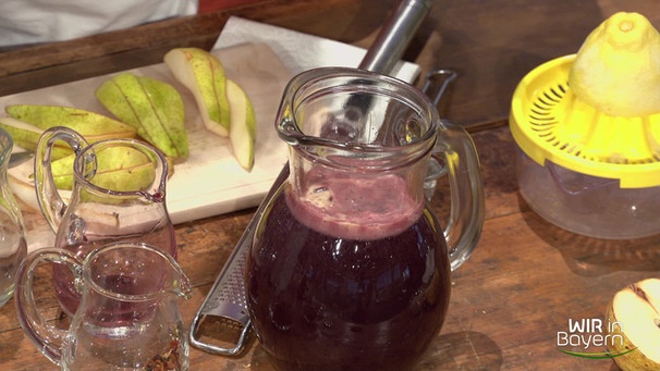 Winterlicher Fruchtpunsch in einer Glaskanne auf einem Tisch mit einer Saftpresse und Birnen | Bild: Wir in Bayern