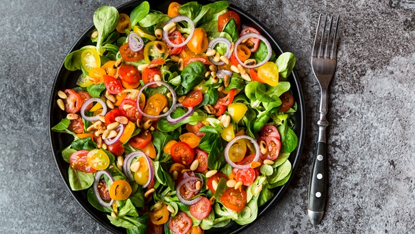 Ein großer gemischter Salat mit Feldsalat, roten und gelben halbierten Coktailtomaten, roten Zwiebelscheiben | Bild: mauritius images / Westend61 / Sandra Roesch