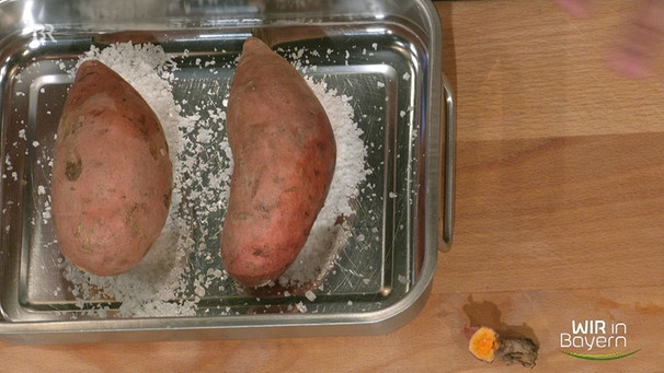 Zwei Süßkartoffeln auf einem Salzbett in einer Auflaufform von oben fotografiert | Bild: Wir in Bayern