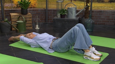 Physiotherapeutin Andy Sixtus zeigt eine Übung gegen Spannungskopfschmerzen: Armheben in Rückenlage | Bild: BR