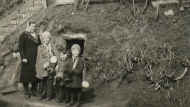 Familie vor Erdbunker während des Krieges | Bild: BR