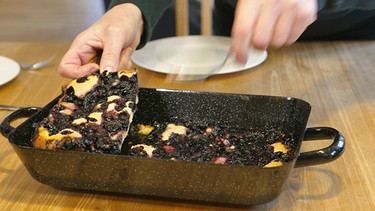 Nach dem Backen wird der fertige Hoiberdatschi in der Reine in Stücke geschnitten, die mit einem Scherer vorsichtig von Rand und Boden gelöst und auf die Teller gehoben werden.  | Bild: BR