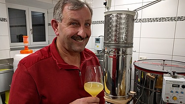 Imker Georg Hofbauer mit einem Glas Met | Bild: BR