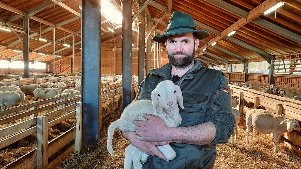 Schäfer Quirin Fröwis mit einem Lamm im Arm | Bild: BR