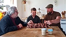 Paul Enghofer (li),  Philipp Rädlinger, (mi) und Peter Raith vor einer Platte mit frischen Wildschweinbratwürsten | Bild: BR / Paul Enghofer