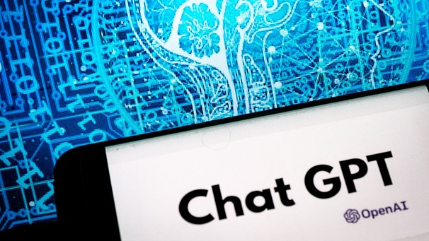 Chat GPT Logo auf dem Display eines Smartphones, im Hintergrund Datenströme | Bild: BR