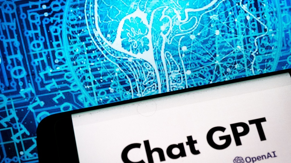 Chat GPT Logo auf dem Display eines Smartphones, im Hintergrund Datenströme | Bild: BR