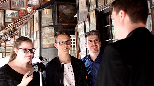 Zwei Jugendliche interviewen einen Pfarrer vor der Kapelle in Altötting. | Bild: BR