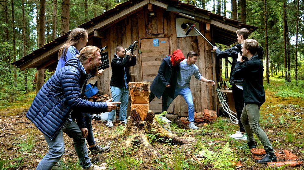 Schüler drehen vor einer Holzhütte eine Szene. | Bild: BR