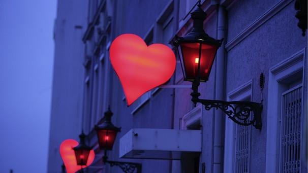 Rotlichtviertel: Rote Herzen leuchten neben rotleuchtenden Laternen. | Bild: picture-alliance/Ulrich Baumgarten