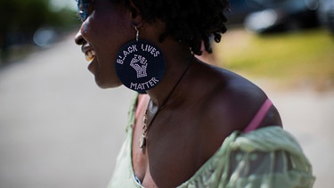Eine lachende Frau mit einem Ohrring, auf dem "Black Lives Matter" steht. | Bild: ap