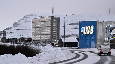 Winterliche Straße mit Auto, dahinter Firmengebäude | Bild: epa