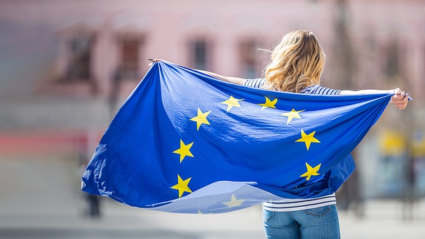 Eine junge Frau hält eine Europaflagge. | Bild: stock.adobe.com/weyo