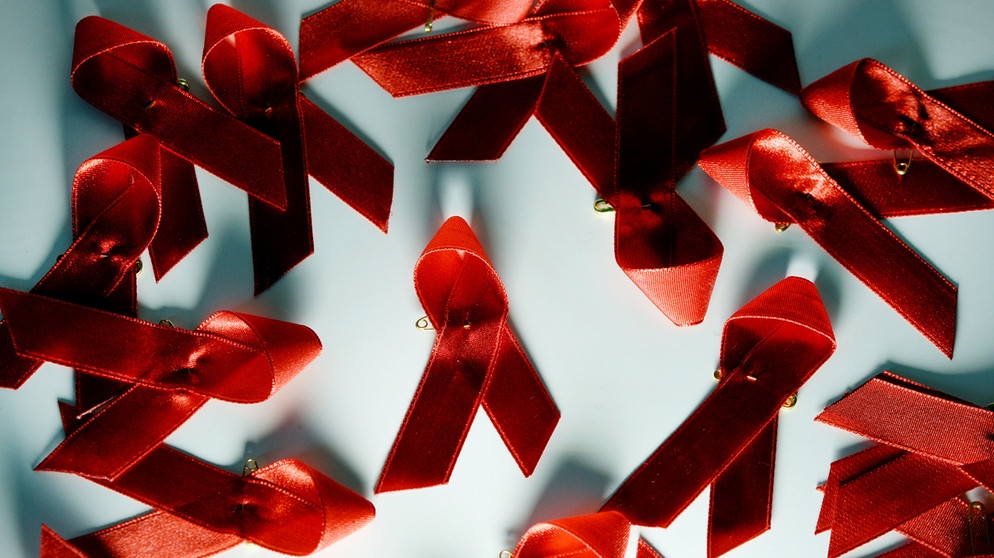 Rote Aids Schleifen liegen auf einem Tisch.  | Bild: dpa-Bildfunk/Jens Kalaene