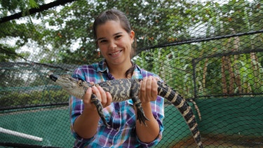 Die Zähne des Alligators | Anna hält einen anderthalb Jahre alten Alligator in den Händen. Ohne Maulkorb könnte sein Biss schon ordentlich weh tun. | Bild: BR | TEXT + BILD Medienproduktion GmbH & Co. KG
