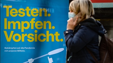 "Testen, Impfen. Vorsicht" steht auf einem Plakat an einer Bushaltestelle am Kurfürstendamm.  | Bild: dpa-Bildfunk/Paul Zinken