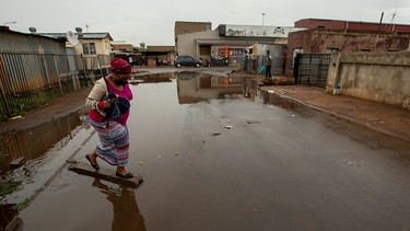Eine Frau, die eine Maske zum Schutz vor dem Coronavirus trägt, überquert eine Straße in Südafrika. | Bild: dpa-Bildfunk/Themba Hadebe