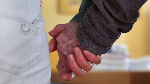 Eine Frau führt eine Bewohnerin der Demenz-Wohngemeinschaft an der Hand. | Bild: dpa-Bildfunk/Karl-Josef Hildenbrand