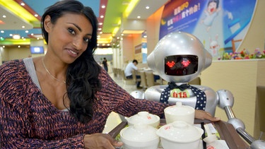 Im "Robot Restaurant" in China kochen und bedienen Roboter. Shini Somara mit einer "Bedienung" in Shanghai. | Bild: BBC 2015/BR