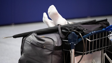 Füße ruhen auf einer Reisetasche | Bild: picture alliance/dpa / Boris Roessler