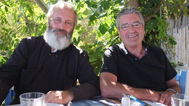 Franz Gernstl mit Pfarrer Josef Eckert (links) beim Mittagessen in einer Taverne in Keratea. | Bild: BR/megaherz gmbh/