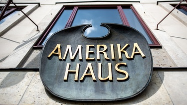Ein Schild mit der Aufschrift „Amerikahaus“ ist vor dem Amerikahaus zu sehen.
Aufnahme | Bild: picture alliance/dpa | Matthias Balk