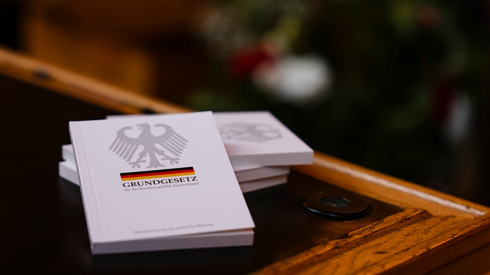 Vier Bücher mit dem Grundgesetz liegen während einer Einbürgerungsfeier auf einem Tisch im Ratssaal des Kieler Rathauses. In der Landeshauptstadt wurden im Jahr 2022 781 Personen eingebürgert. | Bild: dpa-Bildfunk/Frank Molter