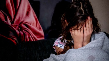 Mädchen vergräbt Gesicht in den Händen. | Bild: dpa/picture alliance
