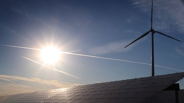 Bayern, Kitzingen: Ein Windrad steht hinter den Solarzellen einer Solarkraftanlage im Sonnenschein.  | Bild: dpa-Bildfunk/Karl-Josef Hildenbrand