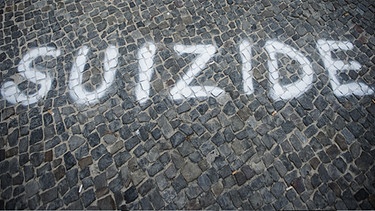 Der Schriftzug SUIZID ist mit weißer Farbe auf Pflastersteine geschrieben | Bild: picture-alliance/dpa
