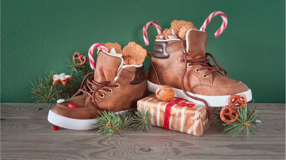 Zwei mit Süßigkeiten befüllte Schuhe. Warum stellen wir am Nikolaustag unsere Schuhe vor die Tür? Und was haben der Heilige Nikolaus und der Weihnachtsmann eigentlich miteinander zu tun?  | Bild: Wochit/Getty Images