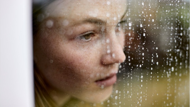 Eine junge Frau sieht aus einem verregneten Fenster hinaus. Die Zahl einsamer Menschen in Deutschland steigt - besonders unter Jugendlichen und jungen Erwachsenen. Wie äußert sich Einsamkeit und was könnt ihr dagegen tun? | Bild: Wochit/ Getty Images/ Oliver Rossi