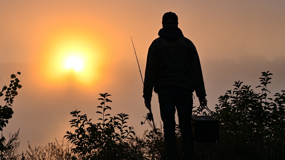 Ein Angler steht im dichten Morgennebel vor dem farbenprächtigen Sonnenaufgang am deutsch-polnischen Grenzfluss Oder. | Bild: picture alliance/dpa/dpa-Zentralbild | Patrick Pleul