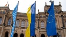 Bayern, München: Vor dem bayerischen Landtag wehen die Bayerische (l-r), die Ukrainische und eine Europa Flagge. Russische Truppen haben 24.02.2022 einen Angriff auf die Ukraine gestartet. | Bild: dpa-Bildfunk