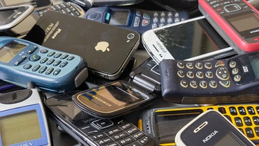 Ausrangierte Mobiltelefone liegen auf einem Tisch. Nach Angaben des Digitalverbandes Bitkom bewahren die Menschen in Deutschland über 200 Millionen Handys und Smartphones zu Hause auf (Stand: März 2021) | Bild: picture alliance/dpa | Christoph Dernbach