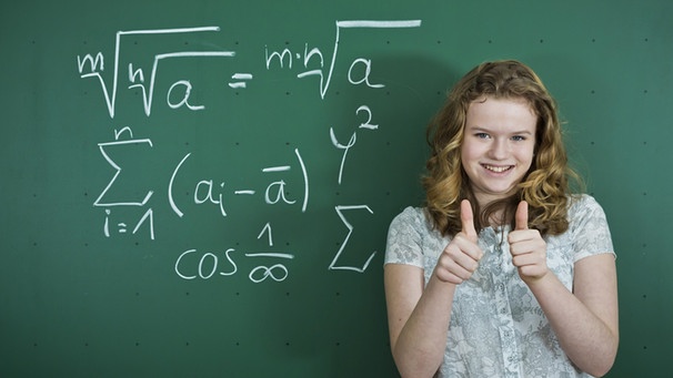 Schülerin vor Tafel mit Formeln mit dem Daumen hoch | Bild: Judith Thomandl/picture alliance/imageBROKER