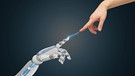 Symbolbild für die Frage nach der Ethik für KI, Menschenhand berührt Roboterhand | Bild: colourbox.com