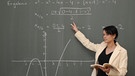 Mathematik-Referendarin steht vor Tafel mit komplexer Formel | Bild: picture-alliance/dpa