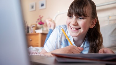Mädchen am Laptop skypend mit Buch vor sich als Symbolbild für "DaZ-Buddies" | Bild: colourbox.com