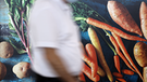 Symbolbild für Campus talks: Passanten laufen an einer Außenwerbung an einem REWE-Markt in Köln vorbei, die frisches Gemüse zeigt.  | Bild: picture alliance / Geisler-Fotopress | Christoph Hardt/Geisler-Fotopres