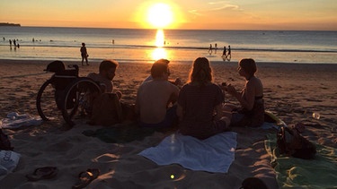 Im Sand sitzen und den Sonnenuntergang genießen: Thomas mit seinen Freunden am Strand von Bali | Bild: Thomas Wiest