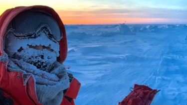 Wissenschaftlerin, warm eingepackt am Nordpol; im Hintergrund Farbenspiel am Himmel. | Bild: Stefanie Arndt