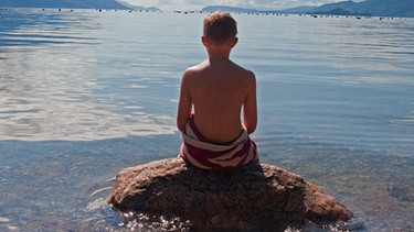 Junge auf einem Stein am See | Bild: colourbox.com