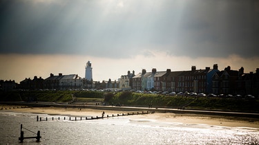 Stadt an der Küste Englands mit dunklem Himmel. Sonnenstrahlen brechen durch. | Bild: colourbox.com