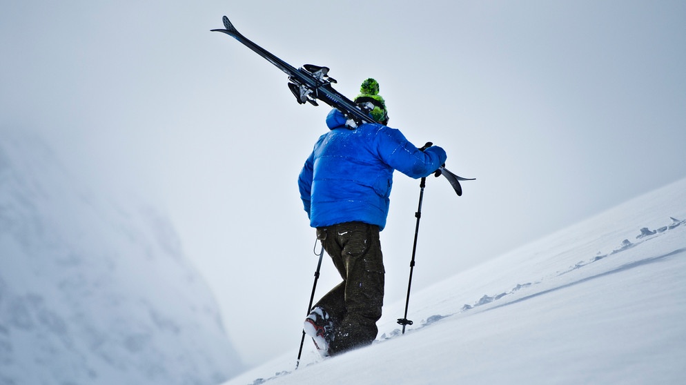 Skifahrer wandert im Schnee einen Berg rauf mit seinen Skiern auf der Schulter. | Bild: colourbox.com