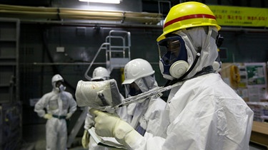 Menschen in Schutzkleidung führen Strahlungsmessungen im Atomkraftwerk Fukushima durch, Japan | Bild: picture alliance / AP Images | Kimimasa Mayama