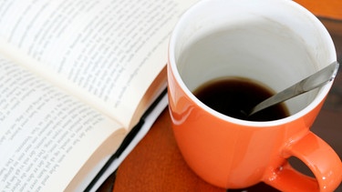 Eine Tasse mit Kaffee neben einem aufgeschlagenen Buch | Bild: colourbox.com