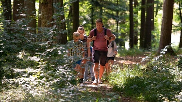 Eine Familie wandert durch einen Wald | Bild: Michael Koch