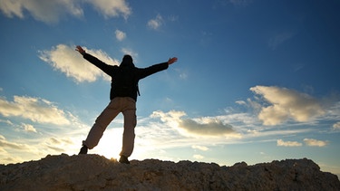 Mann steht auf einem Felsen und schaut gen Himmel | Bild: colourbox.com