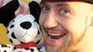 Der Musiker, Komiker und Schauspieler Bürger Lars Dietrich präsentiert einen Stofftier-Wecker namens "Good Morning Buddy". | Bild: picture-alliance/dpa